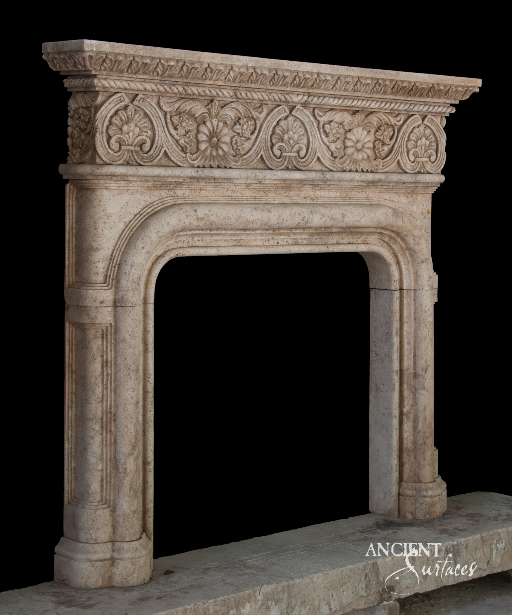 Honey toned reclaimed limestone fireplace mantel with a palmette and rosette frieze under a leaf tip cornice, above a reeded basket arch opening