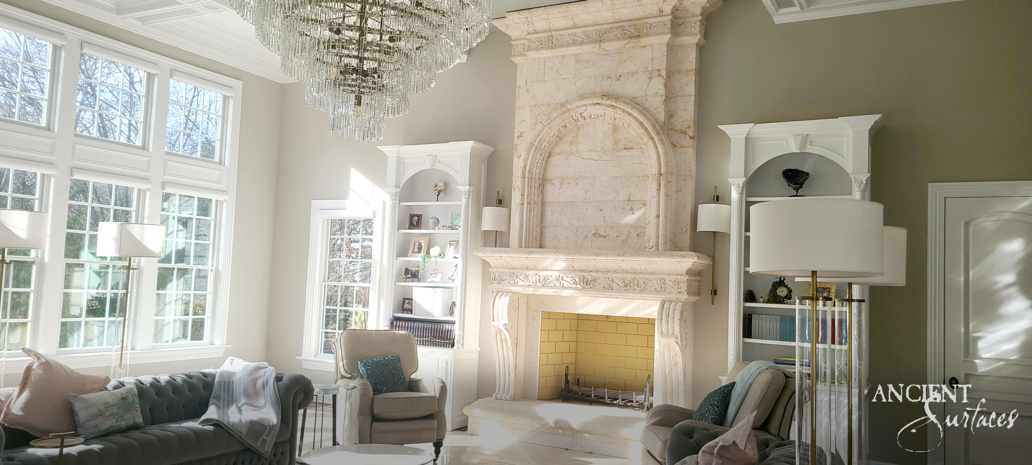 Full height reclaimed limestone chimneypiece with a tall arched overmantel, carved leaf shelf frieze and large scrolled corbel consoles above a raised stone hearth